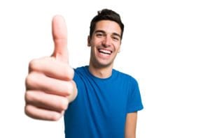 Portrait of man in blue shirt giving thumbs up standing in front of white background