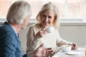 woman with all on four dental implants gossiping over coffee