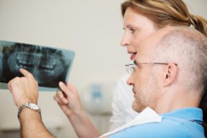 Oral surgeon and patient looking at dental x-rays