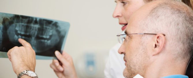Oral surgeon and patient looking at dental x-rays