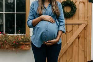 pregnant woman holding belly and wondering if she can get her wisdom teeth removed while pregnant