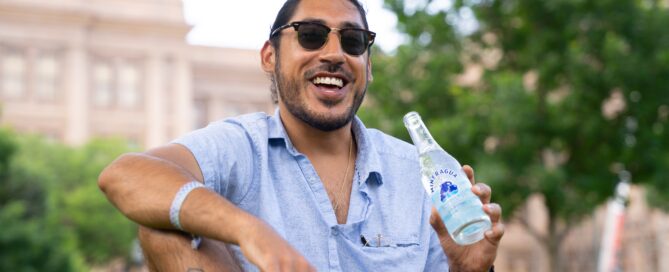 man drinking water bottle sitting in a park