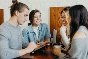 group of four friends talking at a table in a coffee shop