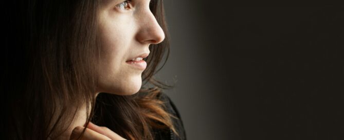 Woman in black sweatshirt with her hand by her throat